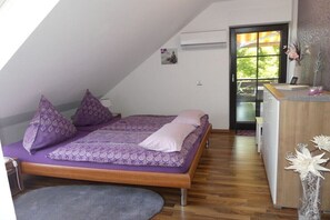 A bedroom with a bed, pillows, a desk, and a window with a view.