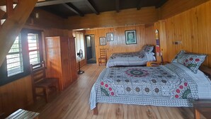 Una cabaña de madera con cama, dos sillas, un escritorio y un ventanal.