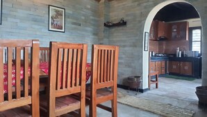 Un comedor con sillas de madera y mantel rojo, una cocina con armarios de madera y una pared de ladrillo.