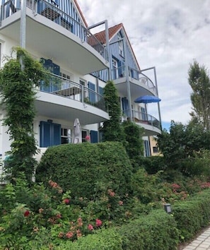 Ein mehrstöckiges Gebäude mit Balkonen, einer Statue und üppiger Bepflanzung.