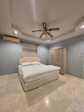 Ein Schlafzimmer mit Bett, Deckenventilator, Klimaanlage und Kleiderschrank.