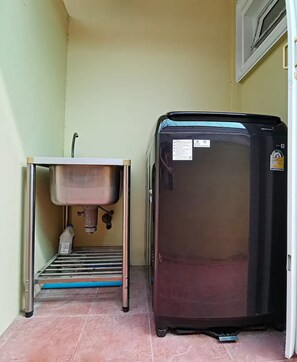 Eine kleine Küche mit Spüle, Kühlschrank und einem Metallregal.