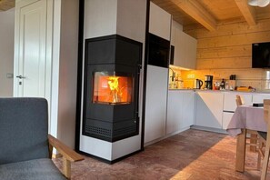 Eine moderne Küche mit Kaminofen, weißen Schränken und einem Essbereich mit Tisch und Stühlen.