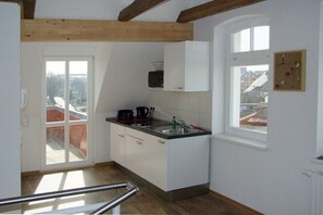 A kitchen with white cabinets, a black countertop, a window, and a view of buildings outside. - Holiday apartment with 1 bedroom (Röbel \/ Müritz)