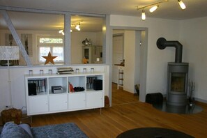 Ein Wohnzimmer mit einer weißen Unterhaltungsanlage, einem großen Spiegel, einer Stern-Dekoration, einem Kamin und einer Treppe, die in einen anderen Raum führt.
