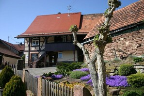 Ein traditionelles Gebäude mit rotem Ziegeldach, einer Steinmauer und einem Holzzaun.