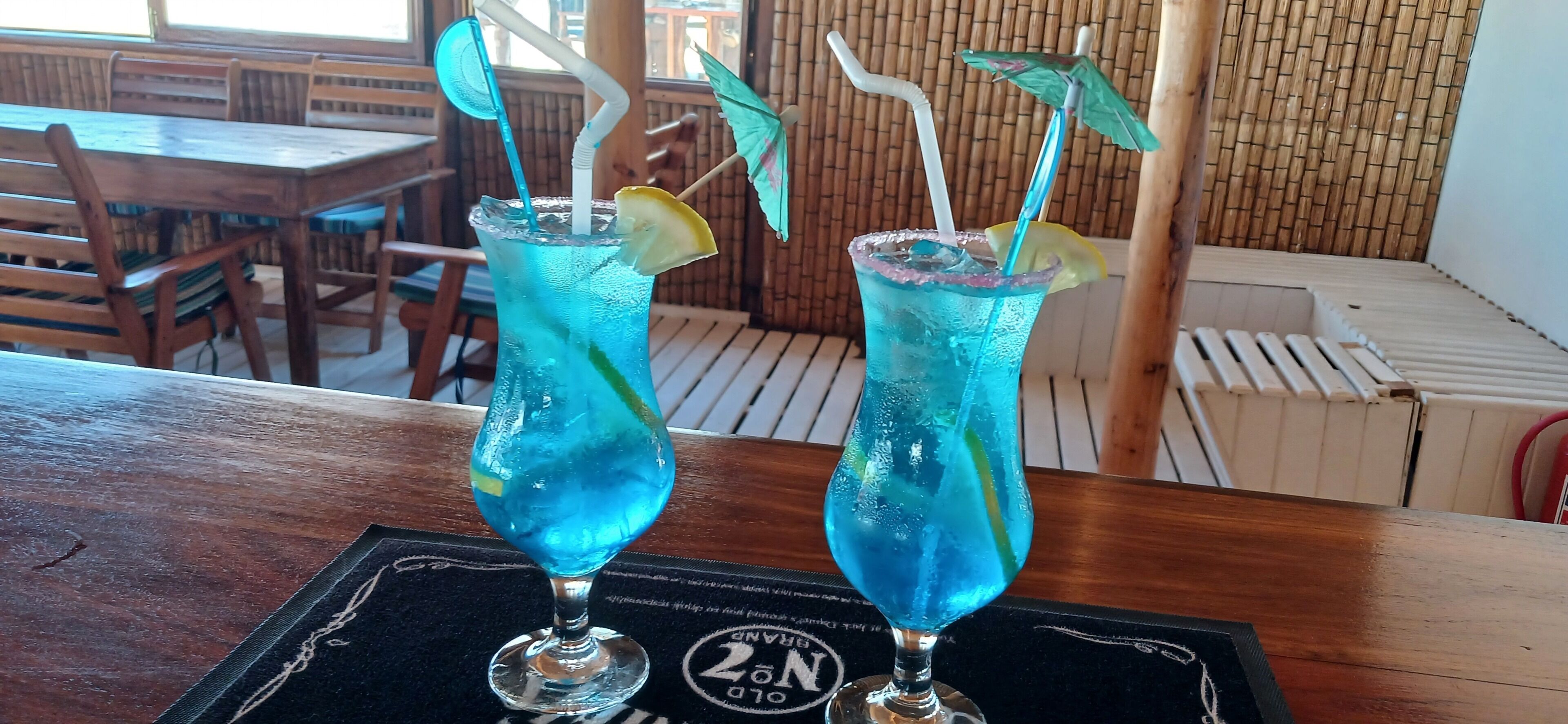 Duas bebidas com canudos e guarda-chuvas sobre uma mesa num restaurante.