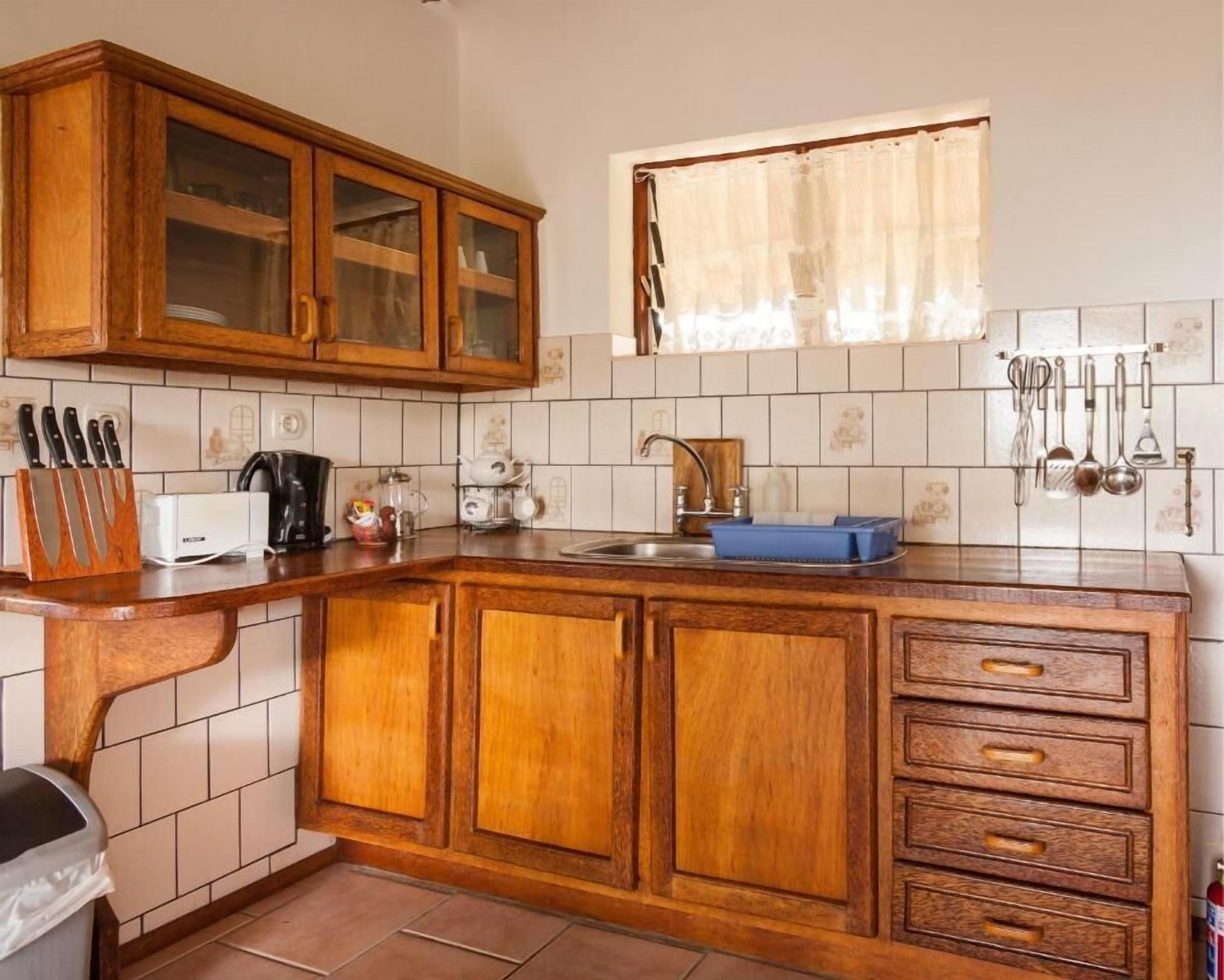 A kitchen with wooden cabinets, a sink, and various utensils.