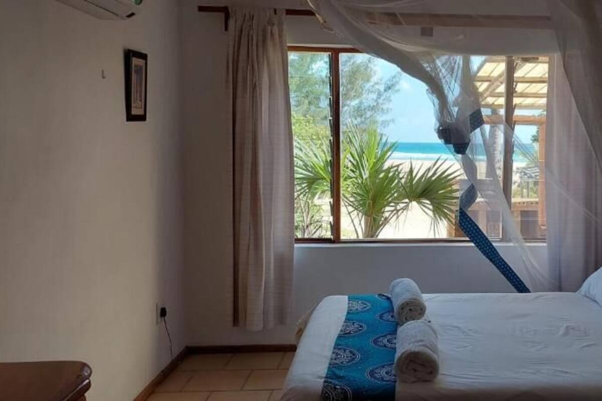 A bedroom with a bed, a window with curtains, and a view of the outdoors.