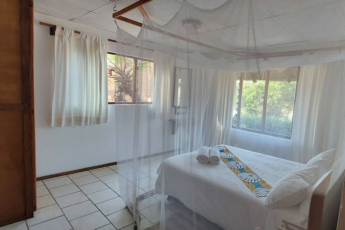 A bedroom with a bed, curtains, and a window.