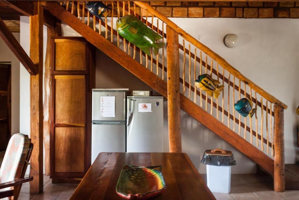 A wooden staircase with a fish decoration, a wooden table with a colorful object, and two refrigerators.