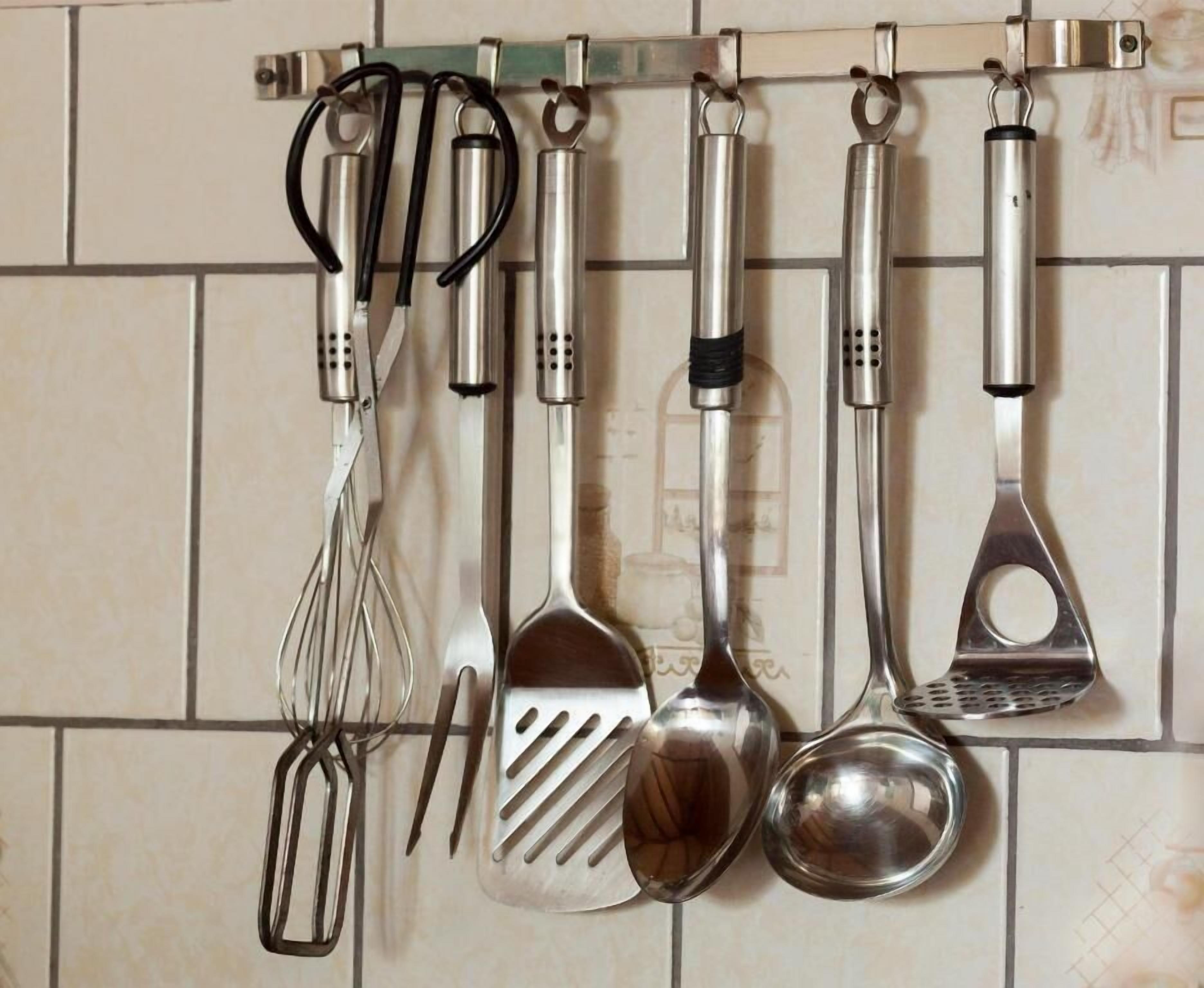 A kitchen with various utensils hanging on a rack.