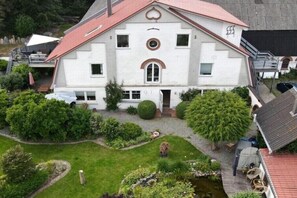Ein großes, weißes Gebäude mit rotem Dach, umgeben von einem gepflegten Garten und einem kleinen Teich.