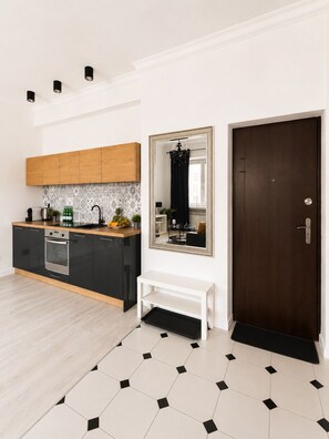 Una cocina moderna con armarios negros, encimera de madera y salpicadero de azulejos.