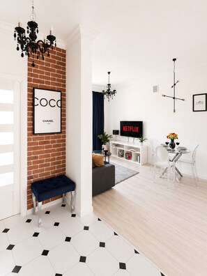 Een moderne woonkamer met een geaccentueerde bakstenen wand, een zwart-wit betegelde vloer, een bank, een houten zitbank, een eethoek met tafel en stoelen, en een televisie waarop 'NETFLIX' wordt weergegeven.