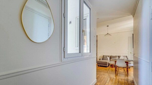 A hallway with a round mirror, a dining area with a table and chairs, and a sofa. - 2BDR/4P apartment near Batignolles (Paris)