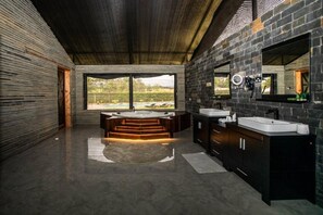 A modern bathroom with a large bathtub, two sinks, and a large mirror. - Kilimanjaro Luxury Camp (Moshi)