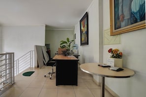Un espace d’accueil comprenant un bureau, une chaise et une petite table sur laquelle se trouvent un téléphone et un panneau.