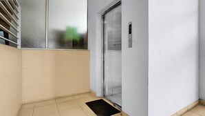 Un couloir avec une porte, une fenêtre et un paillasson.