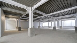Un intérieur de style industriel, caractérisé par son espace vide, ses piliers en béton, son plafond haut et ses grandes fenêtres.