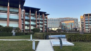 A modern multi-story building with a central courtyard, a covered walkway, and a swimming pool. - Stylish Property With sea View (Jesolo)
