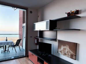 Ein Balkon mit Tisch und Stühlen, einem Fernseher und einem gerahmten Bild an der Wand.