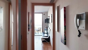 A hallway with a door leading to a room with a desk, chair, and a mounted telephone. - Stylish Property With sea View (Jesolo)
