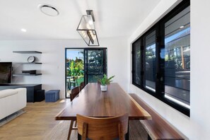 Ein moderner Essbereich mit Holztisch, Stühlen, einem Blumentopf und einem großen Fenster.
