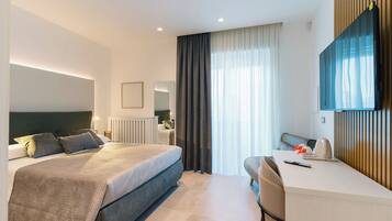 Une chambre d’hôtel moderne dotée d’un grand lit, d’un bureau, d’une chaise, d’un téléviseur à écran plat et d’une fenêtre avec des rideaux.