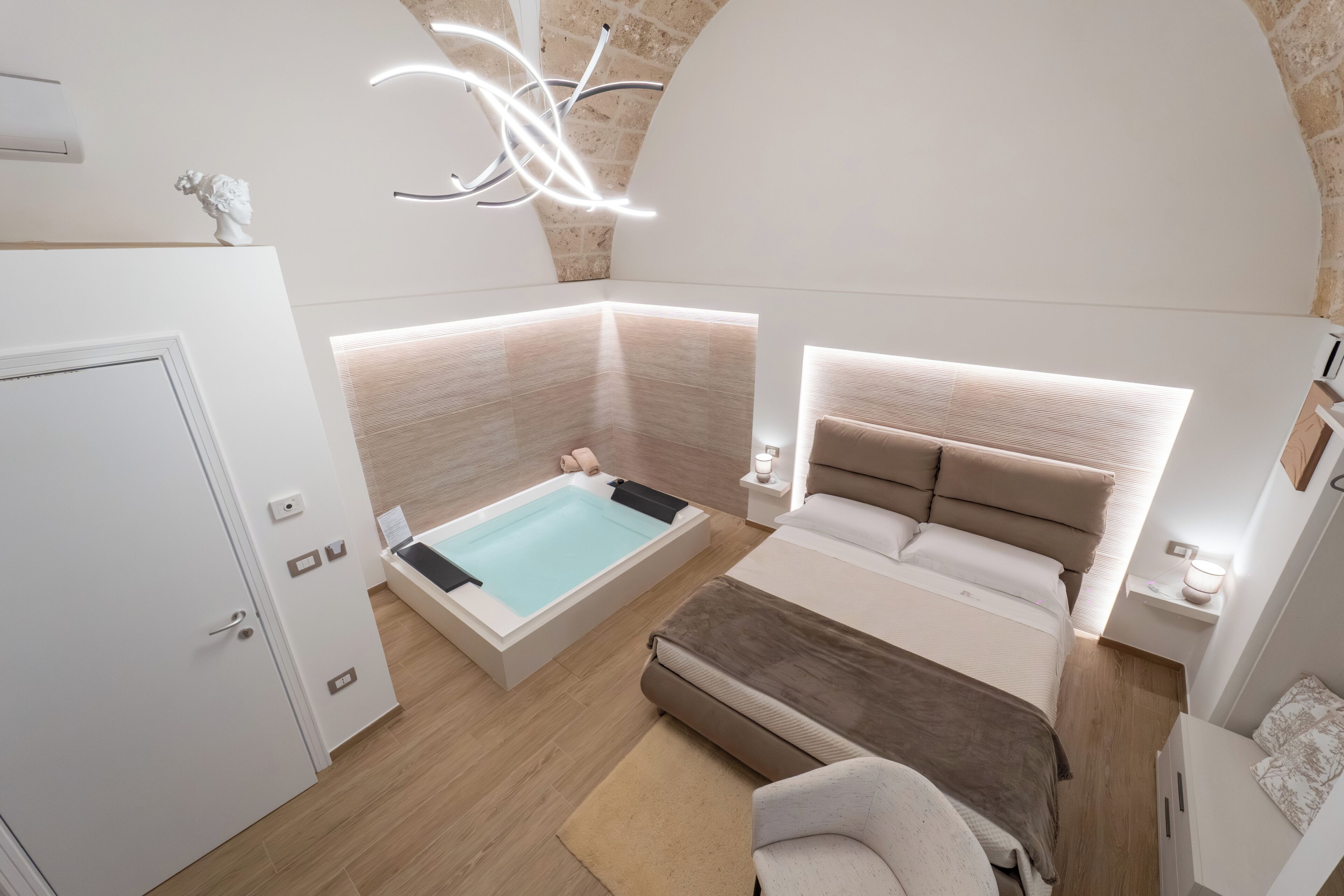 Un dormitorio moderno con una cama grande, una bañera separada y una zona de estar.