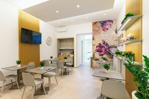 Un comedor moderno con mesas, sillas y plantas en macetas.
