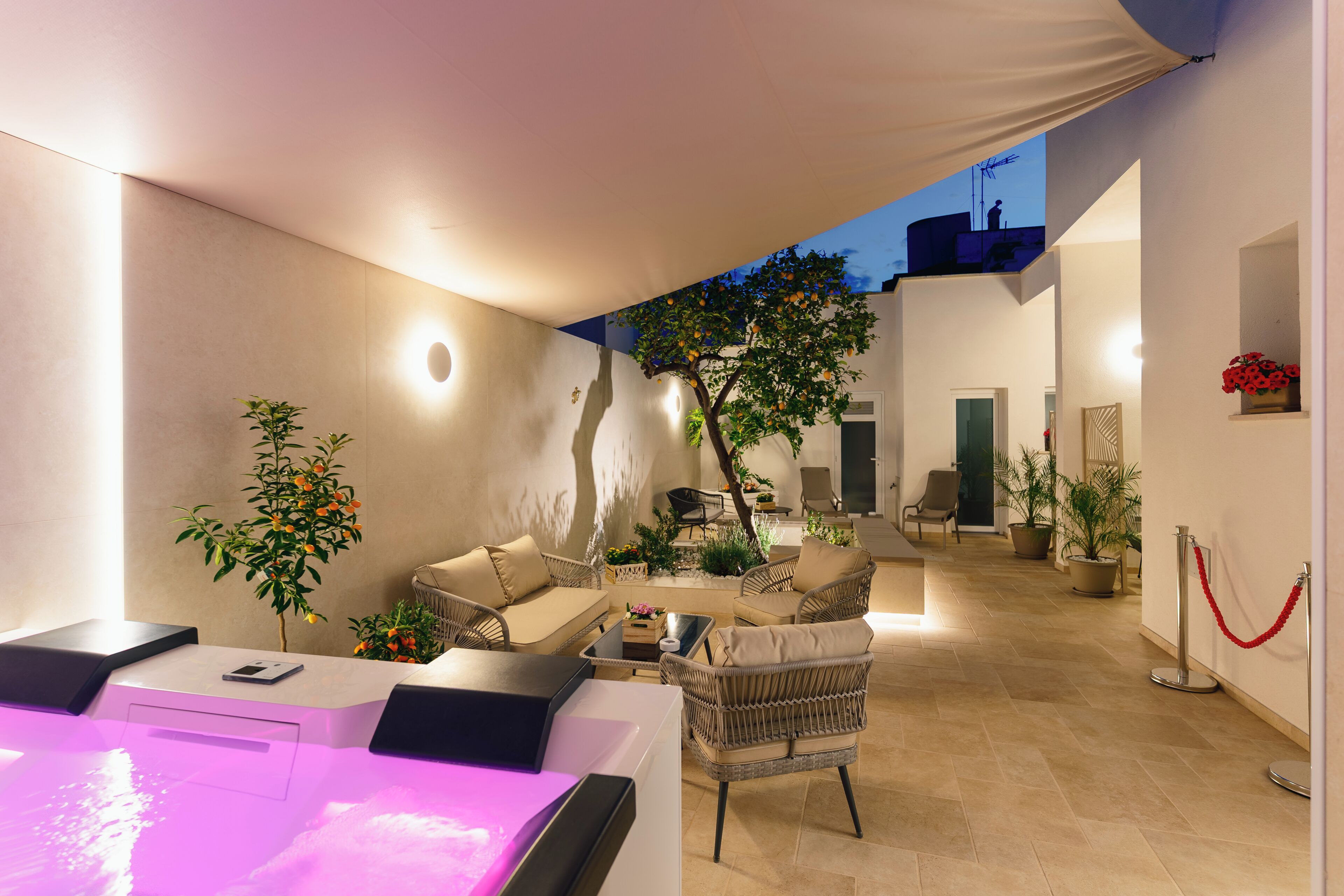 Un espacio exterior moderno con una mesa de billar, sillones reclinables y plantas en macetas.