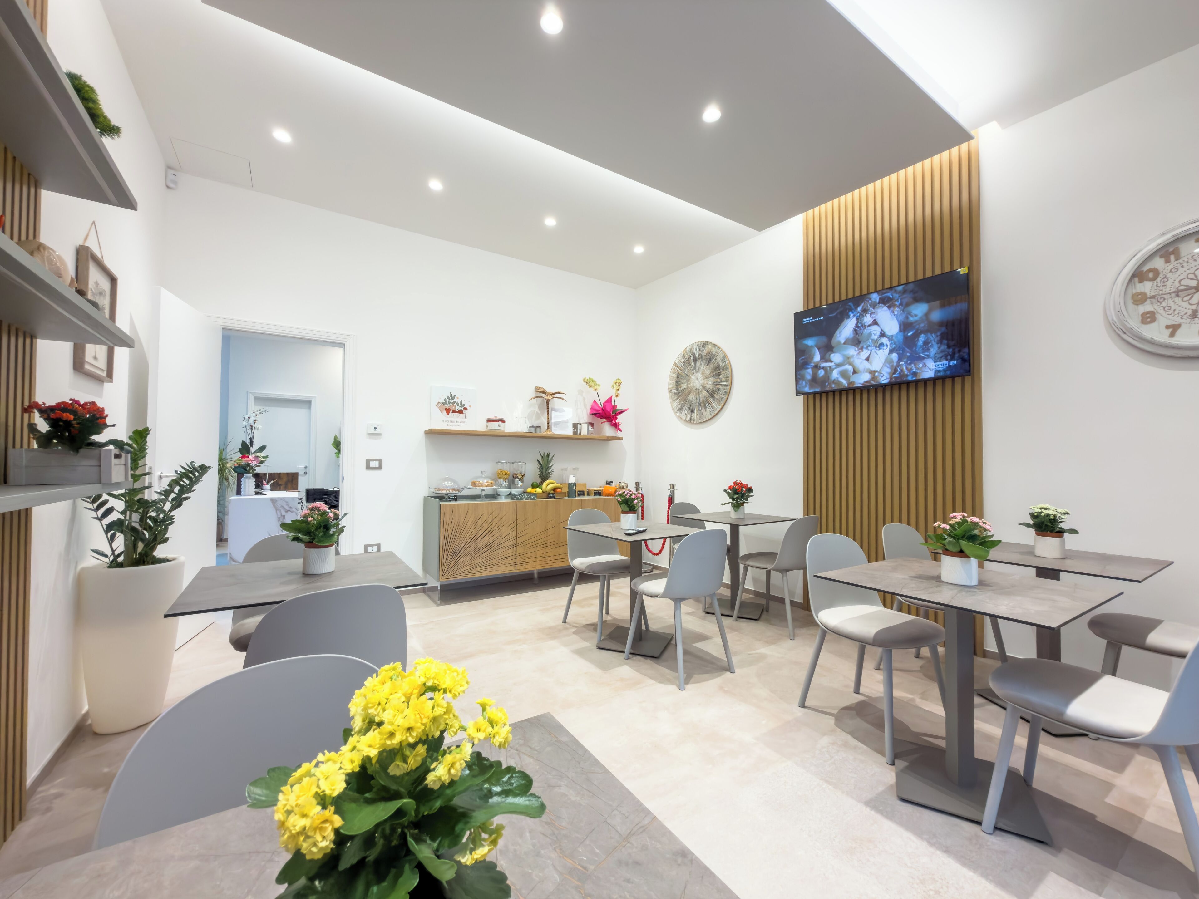 A modern interior with a reception desk, seating area, and a flat-screen TV mounted on the wall.