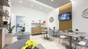A modern interior with a reception desk, seating area, and a flat-screen TV mounted on the wall.