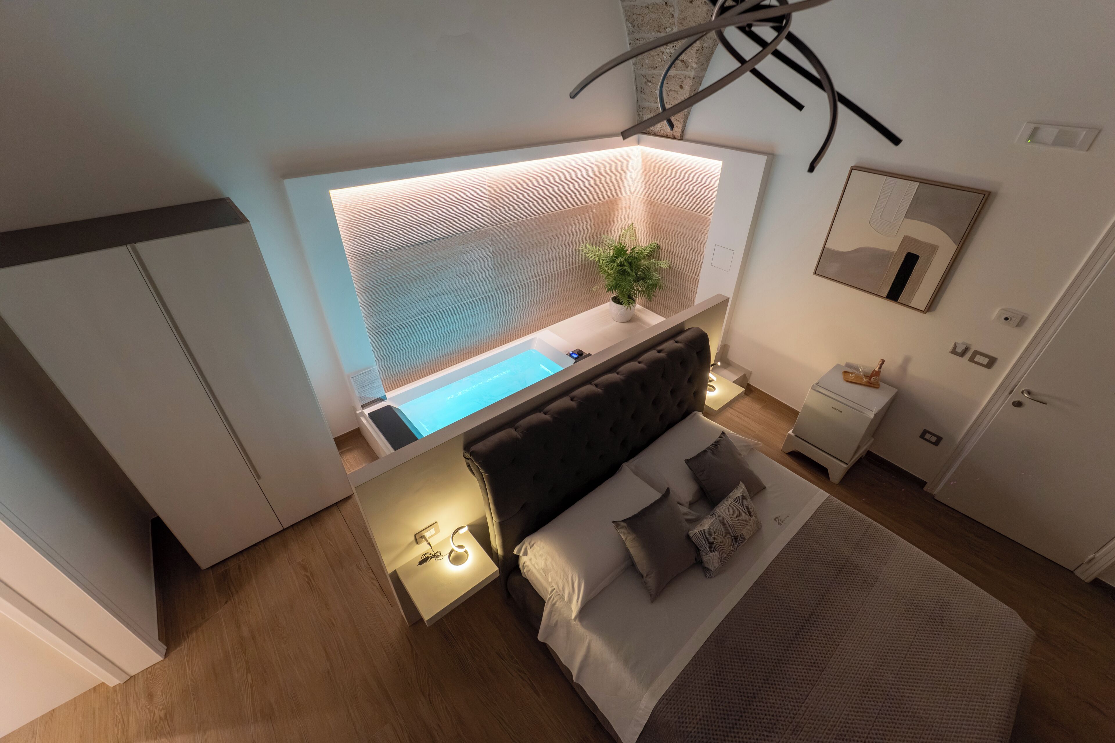 A modern bedroom with a bed, bedside table, nightstand, and a small window.
