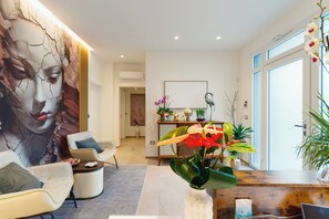 Una sala de estar moderna con un cuadro abstracto grande, un mostrador de recepción y diversas plantas de interior.