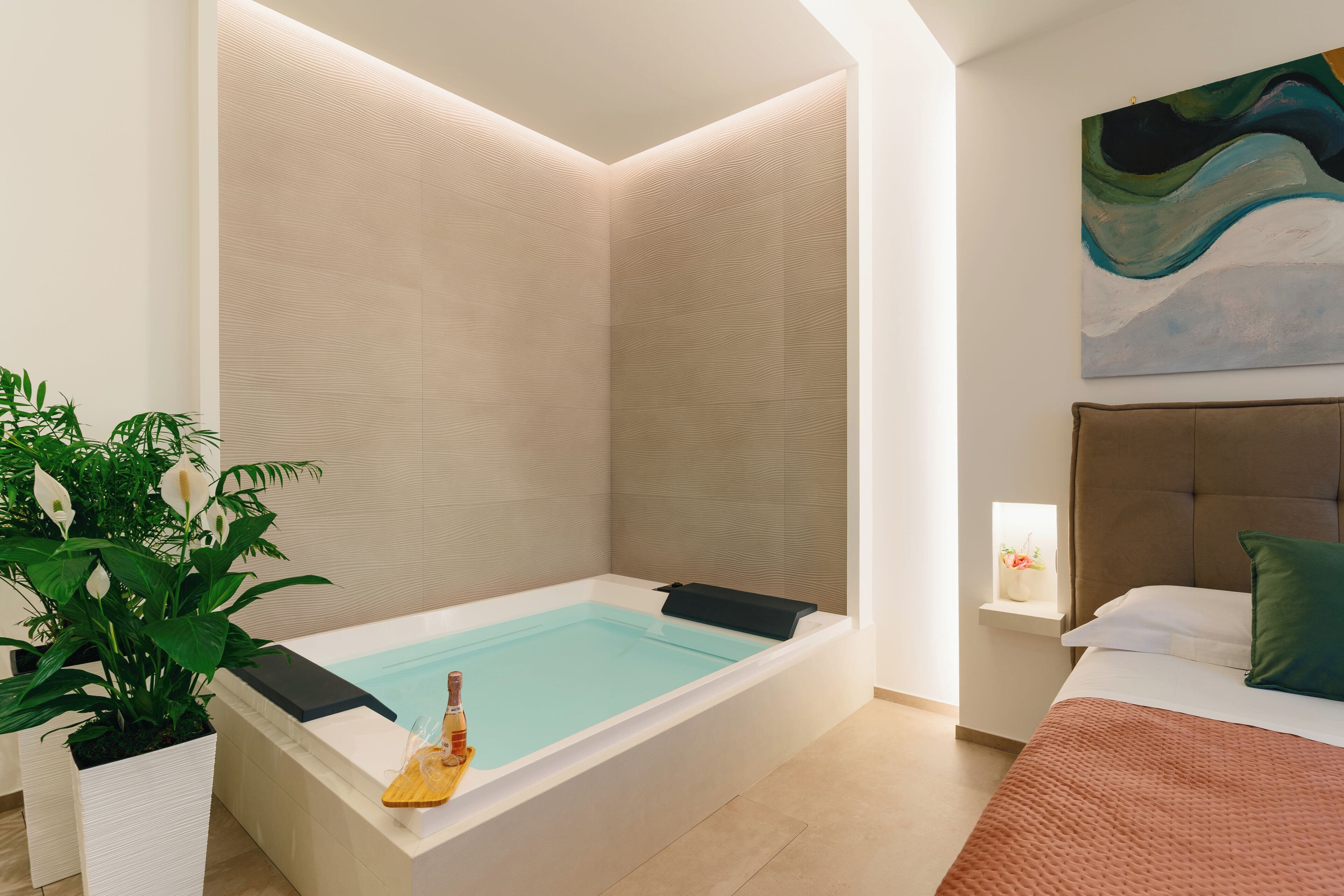Un baño moderno con una bañera independiente, una planta en maceta y un aplique de pared.