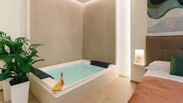 Un baño moderno con una bañera independiente, una planta en maceta y un aplique de pared.