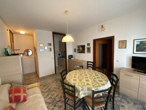 Ein kompakter Wohnbereich mit Essplatz, Küchenzeile und Fernseher.