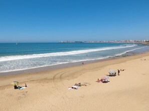 A beach with people sunbathing, umbrellas, and a distant city skyline. - Lumière et Vue Océan by Interhome (Les Sables d'Olonne)