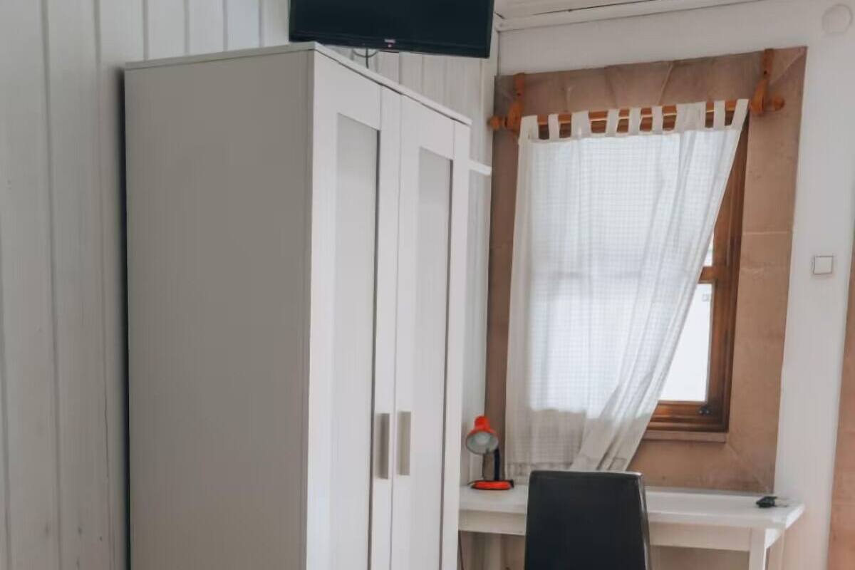 Un dormitorio con cama, escritorio y armario.