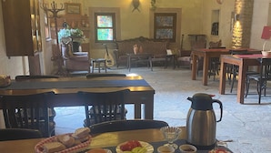 En spiseplads med borde dækket til måltider, en kaffepotte og forskelligt service.