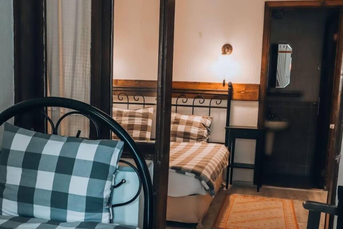 Una habitación con dos camas, una puerta de madera y una mesita.