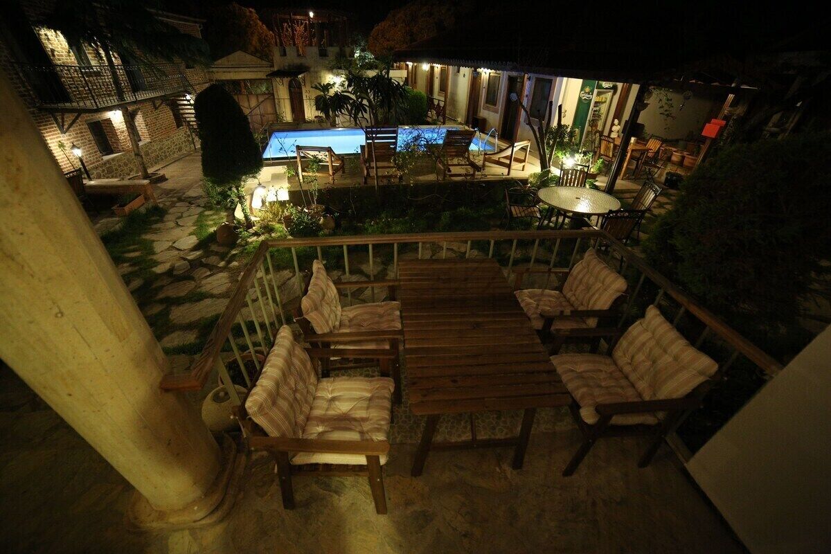 Un patio al aire libre con piscina, mobiliario de madera y un sendero de piedra.
