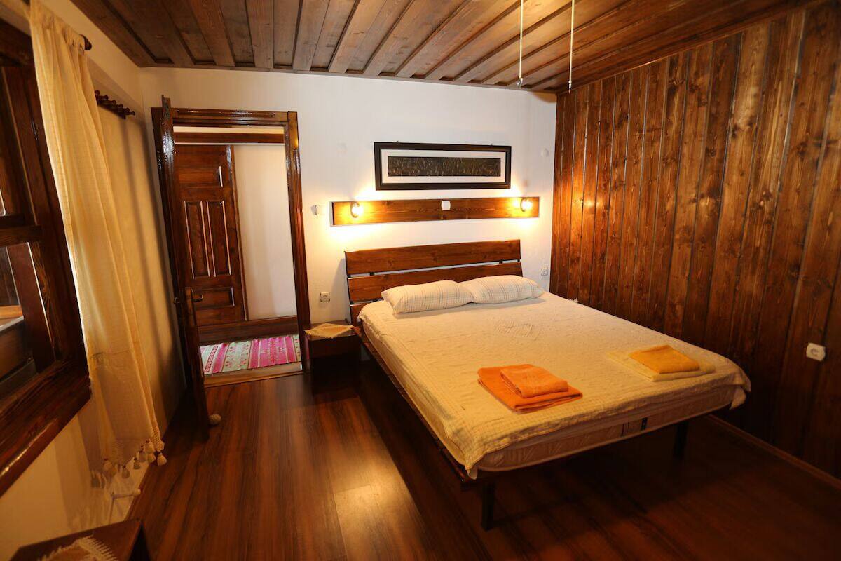 Una habitación con paneles de madera, una cama, un cuadro en la pared y una puerta de madera.