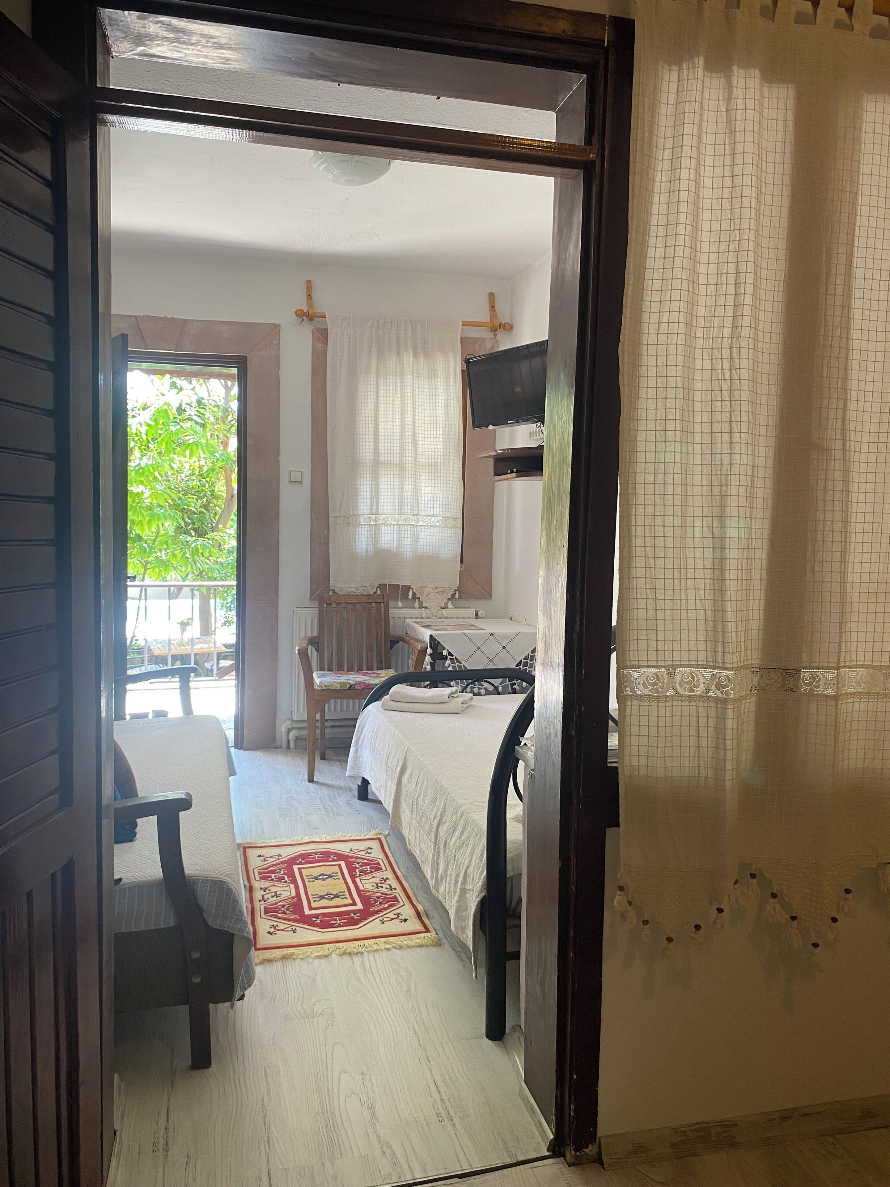 A room with a bed, a chair, a table, and a television.