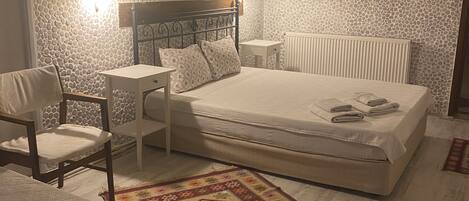 Une chambre à coucher avec un lit, des tables de chevet, une chaise, un tapis à motifs et un ventilateur de plafond.