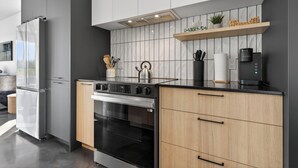 Une cuisine moderne dotée d’un four encastré, d’une cuisinière en acier inoxydable et d’un plan de travail noir.