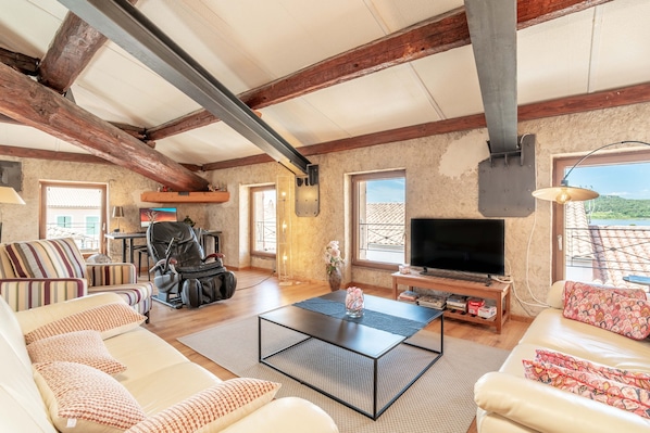 A spacious living room with a sofa, a coffee table, a TV, and a view of the outdoors.
