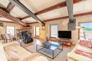 Un salon spacieux comprenant un canapĂ©, une table basse, un tĂ©lĂ©viseur et une vue sur lâextĂ©rieur.